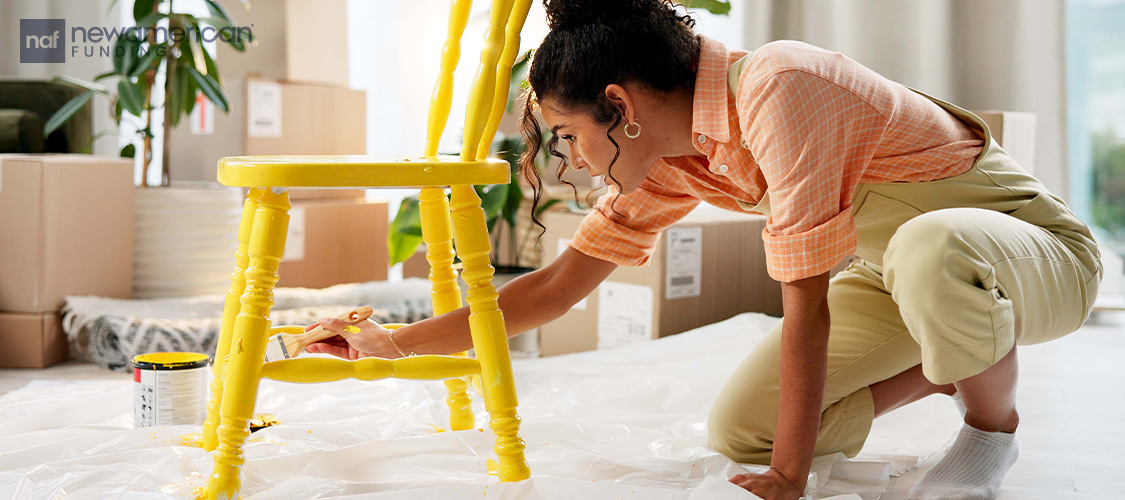 A woman painting a chair yellow.