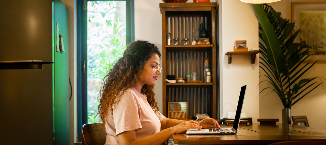 A woman typing at a laptop in a home office.