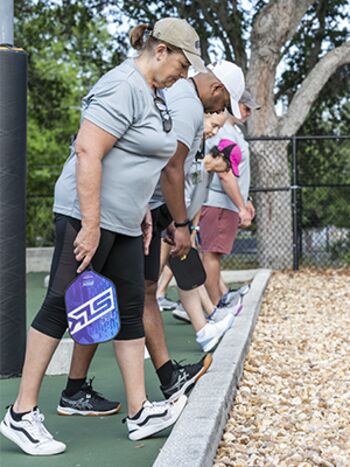 Personal trainer Alex de Cerqueira Santos, center, guides players in a warm-up stretch before the volleying starts. Over the course of the study, Cerqueira noticed the players forming strong bonds.