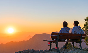 Pokojninsko zavarovanje sklenite, ko ste mladi - mlad par sedi na klopci v hribih in občudije sončni vzhod