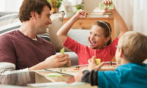 Oče z otrokoma uživa v družabni igri Monopoli.