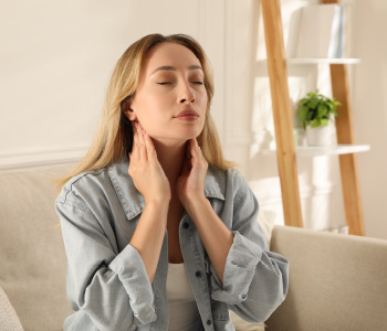 Mlada ženska tipa svoje bezgavke. Simbolna fotografija za pomen rednih pregledov pri zdravniku.