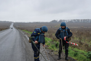 Members of a mine clearance team search a roadside for mines and improvised explosive devices