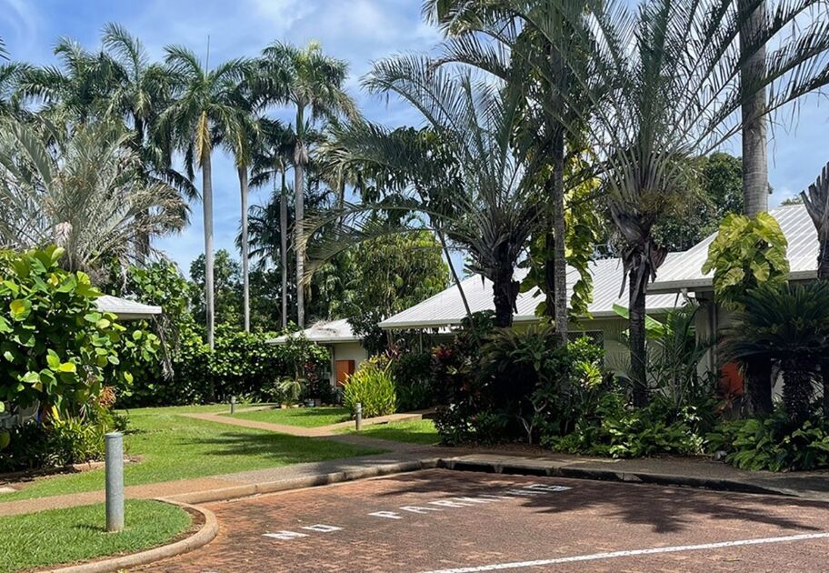 Row of palm-lined Mission Australia Housing social housing units in Darwin with tropical gardens and paved paths