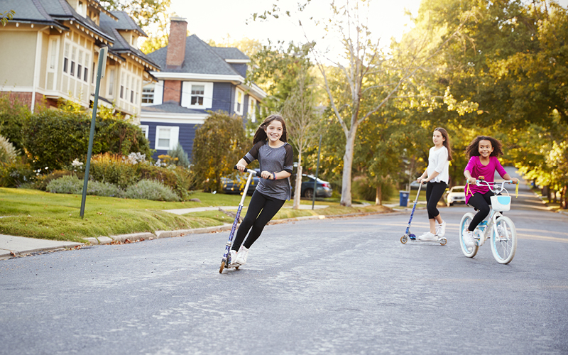 A group of young girls riding scooters