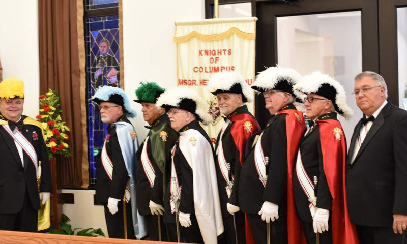 Knights at St.Francis Xavier Church pose by a stained glass window of Father McGivney.