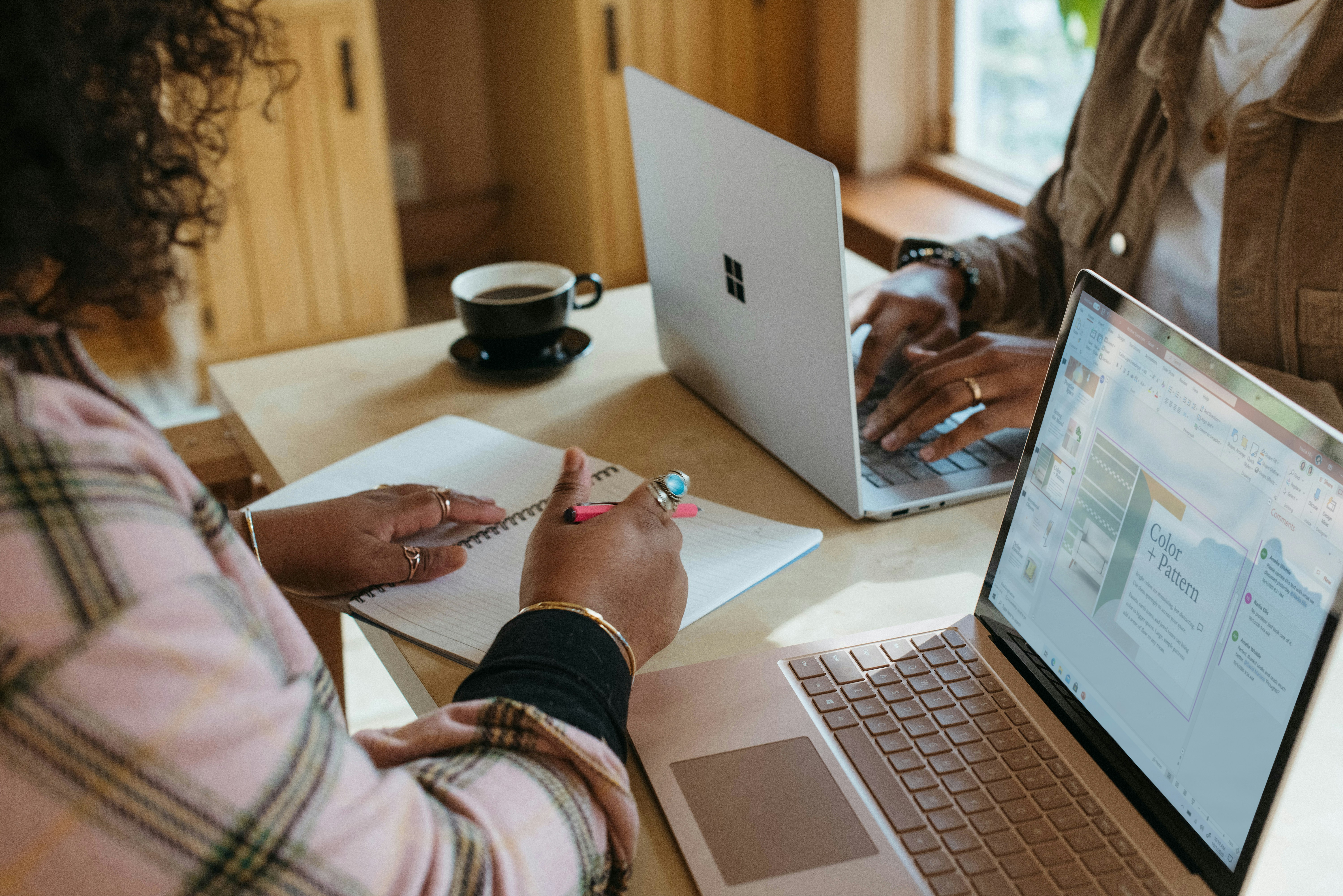 Two ladies sat at desk with laptops and notebooks studying