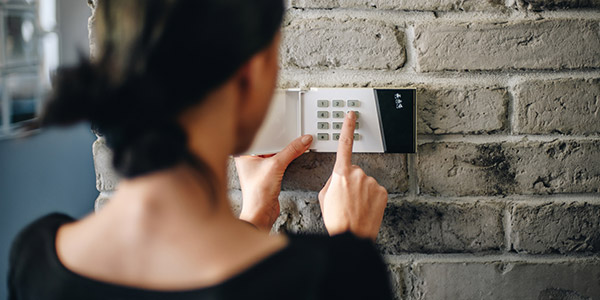 A woman puts a code into a security pad in a home