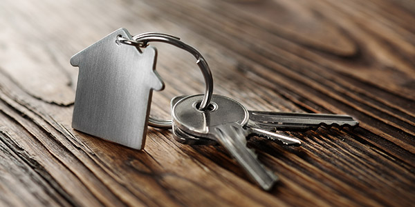 silver keys with a small house key chain sit on a table