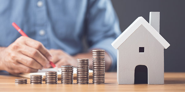 stacks of coins ascending higher towards the height of a house model