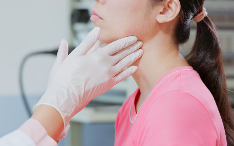 woman receives thyroid exam