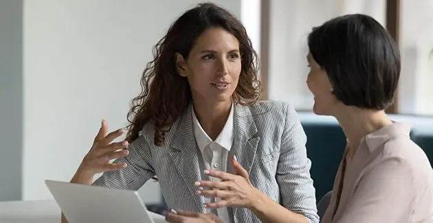 Two women talking over laptop