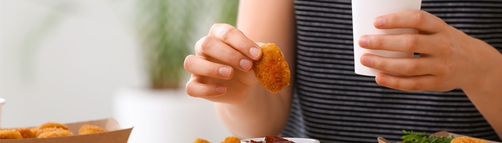 Person holding fried food and a cup.