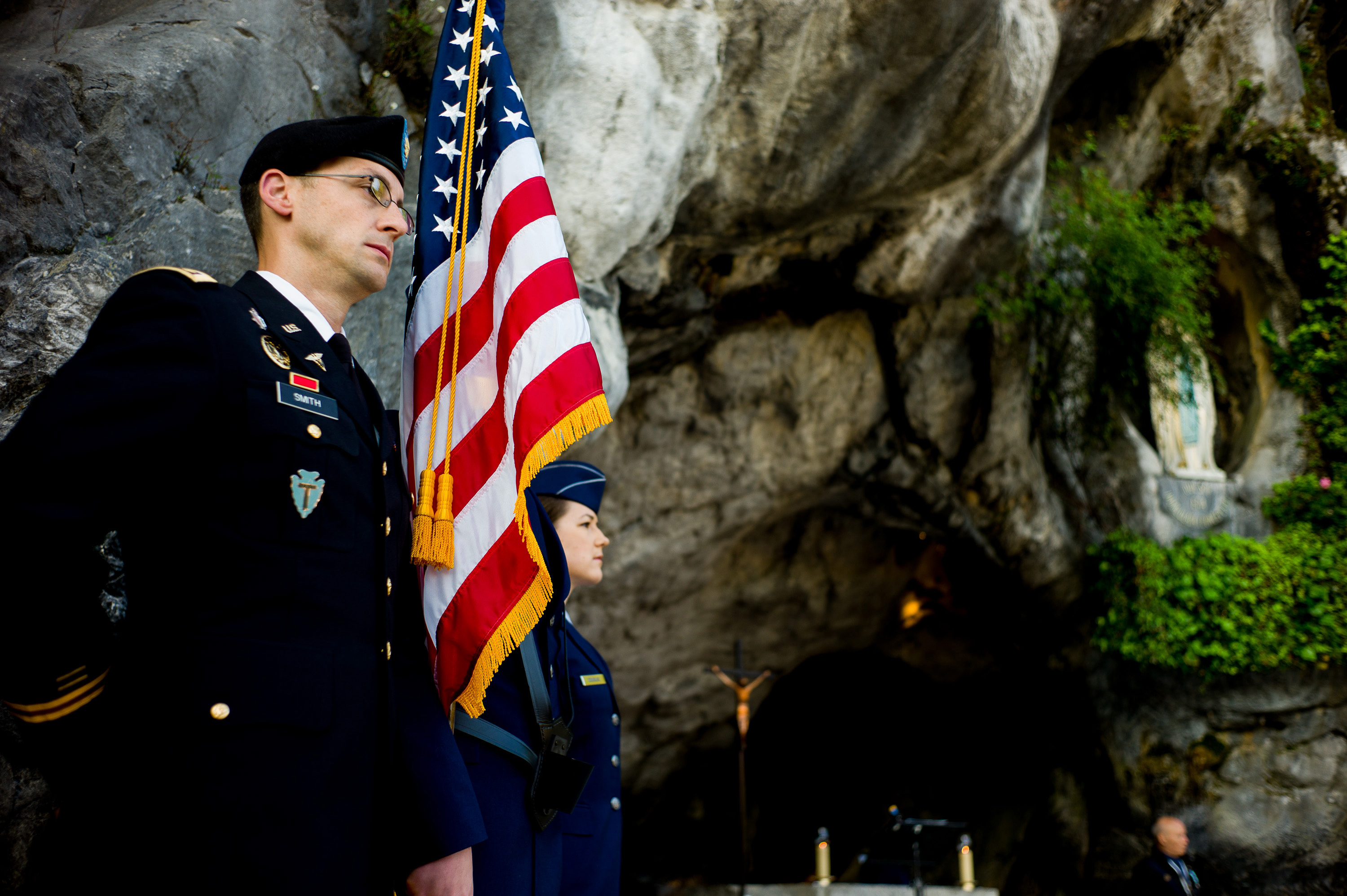 US Soldier stands by American Flags in the grotto at Lourdes.