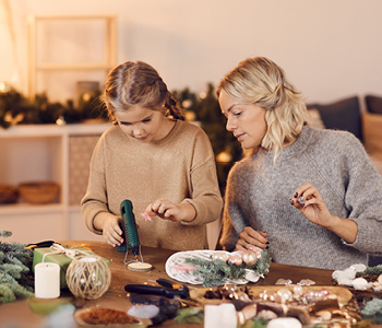 Mama opazuje hčerko, kako ustarja adventni venec in ji pri tem pomaga