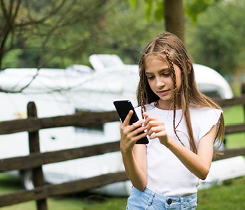 Deklica na počitnicah uporablja telefon brez ozira na varnost na spletu.