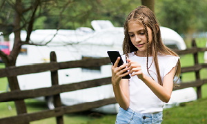 Deklica na počitnicah uporablja telefon brez ozira na varnost na spletu.