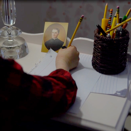 Young woman sitting at desk writing prayer intentions for Father McGivney's intercession.