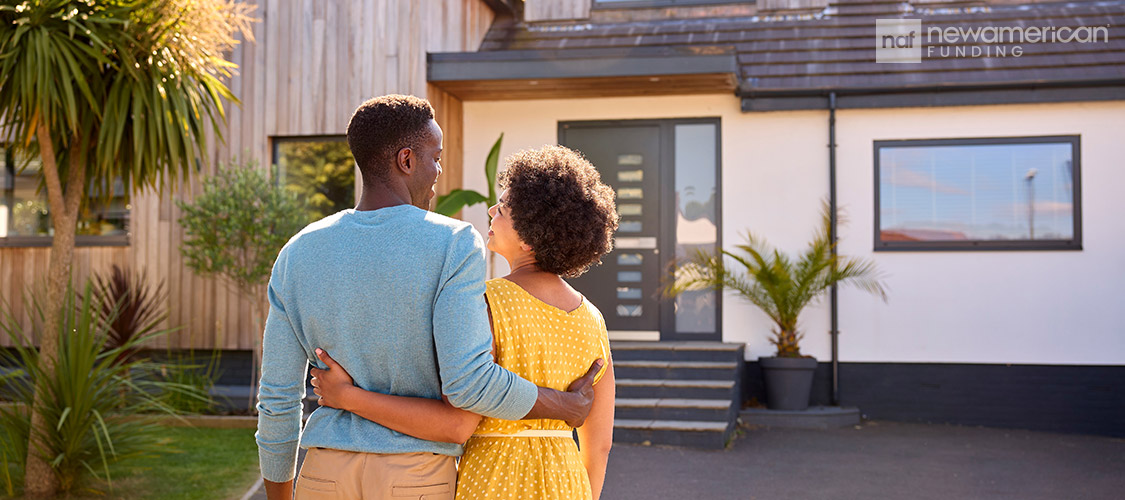 a couple embracing while looking at a house