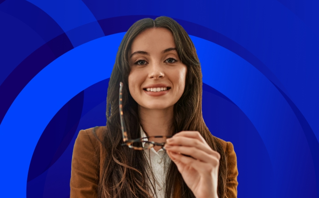 Woman holding her glasses and looking at the camera smiling.