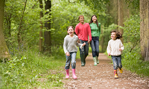 Družina na družinski dan uživa na sprehodu skozi bližnji gozd.