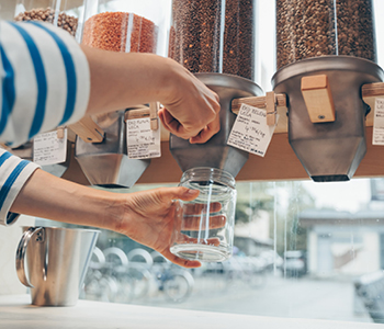 Stranka v trgovini Rifuzl nakupuje izdelke v rinfuzi v svojo trajnostno embalažo.