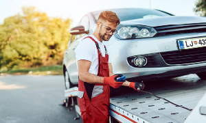 Avtovleka je prišla po okvarjan avto - mehanik avto nalaga na prikolico.