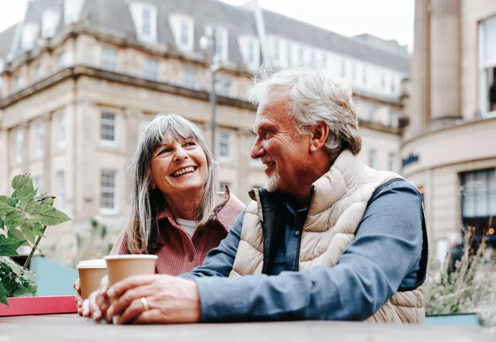  A happy senior couple enjoy a moment together while seated at an outdoor café 
