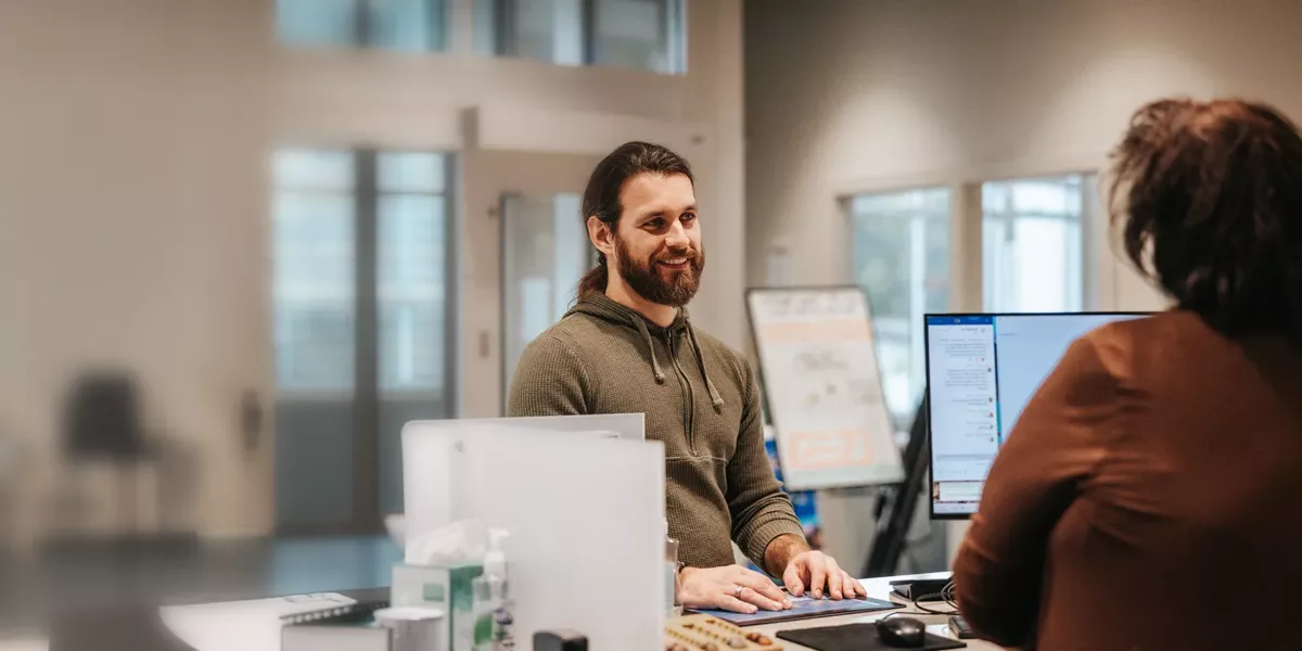 Member speaking with a LMCU representative at a desk in a modern branch office.