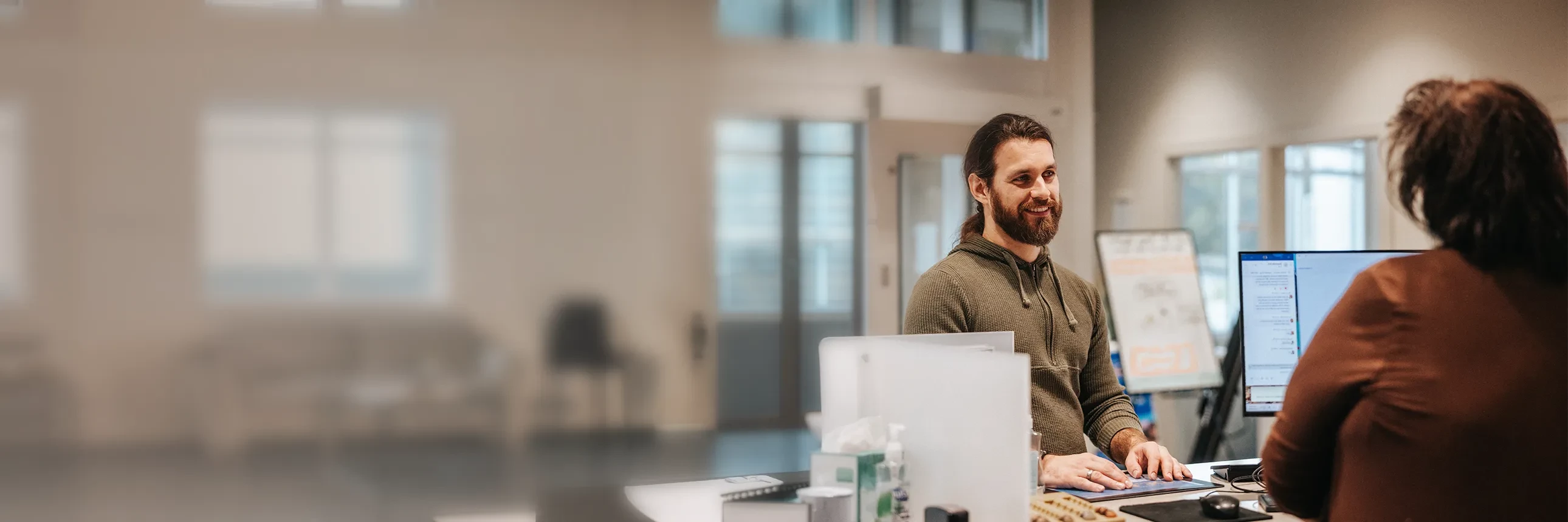 Member speaking with a LMCU representative at a desk in a modern branch office.