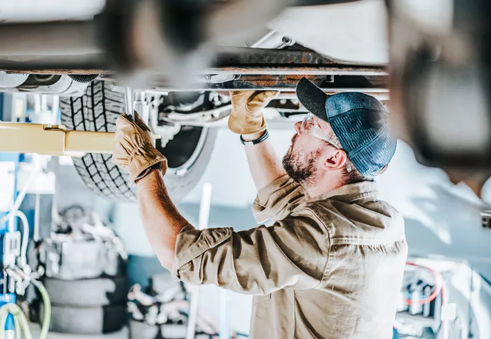  Automotive Industry Car Mechanic Performing a Vehicle Maintenance While on a Lift. 