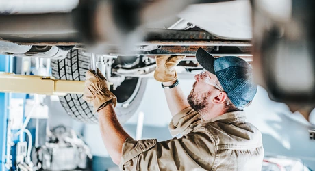  Automotive Industry Car Mechanic Performing a Vehicle Maintenance While on a Lift. 