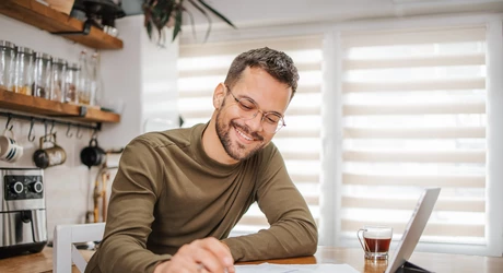 Smiling male at kitchen table going through finances.  